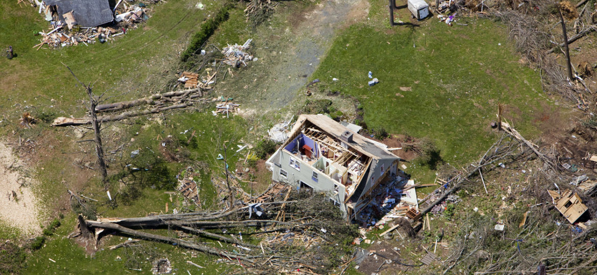 aerial image of a damaged home surrounded by fallen trees after hurricane