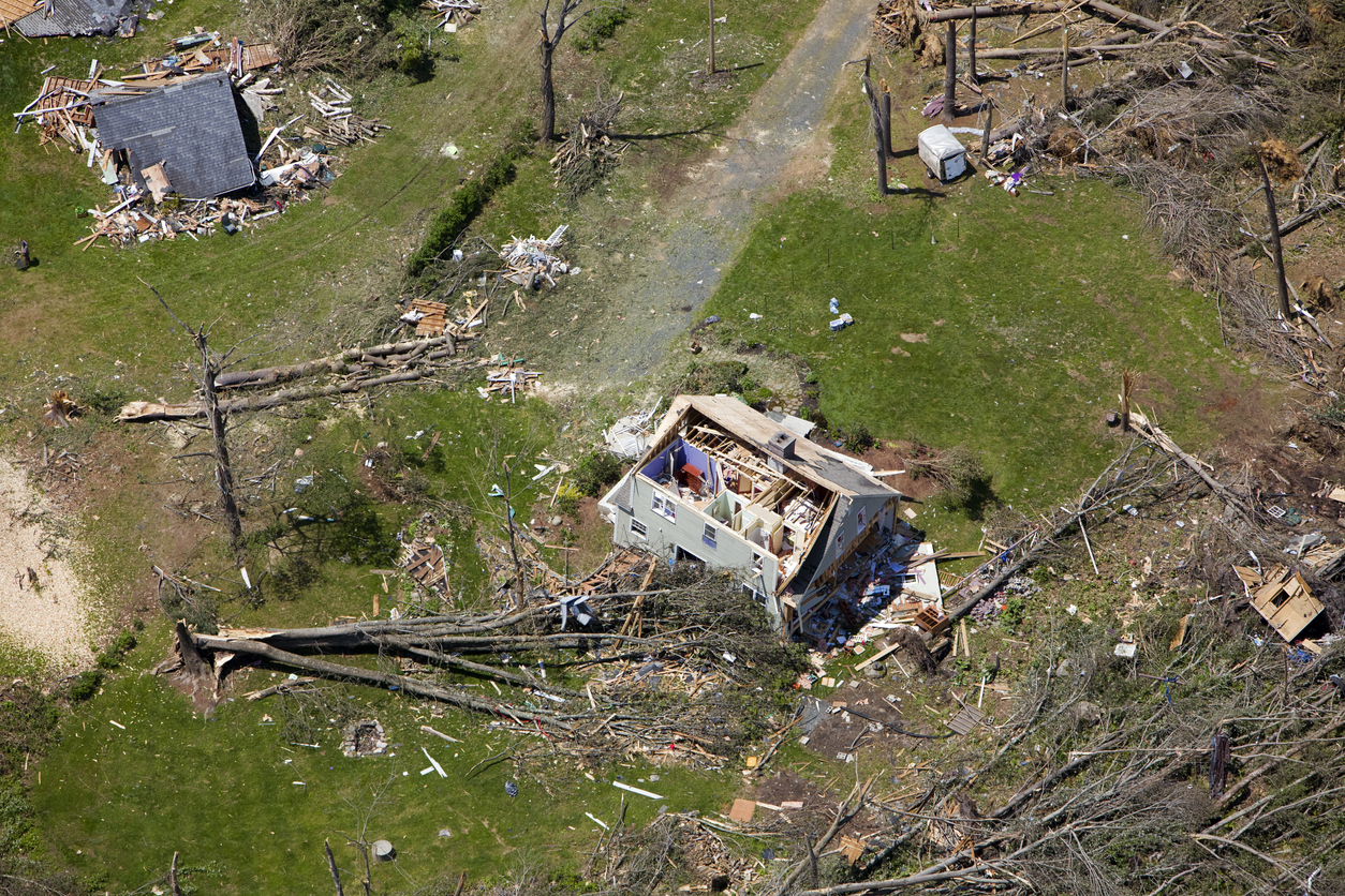 aerial image of a damaged home surrounded by fallen trees after hurricane