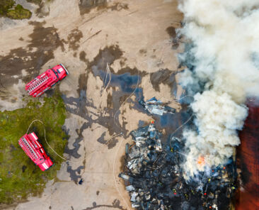 drone image of a factory building on fire with firetrucks nearby