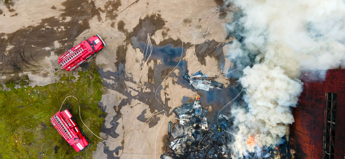 drone image of a factory building on fire with firetrucks nearby