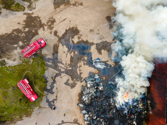 drone image of a factory building on fire with firetrucks nearby