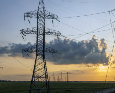 Industrial landscape of a high voltage tower at sunset, urban power lines.