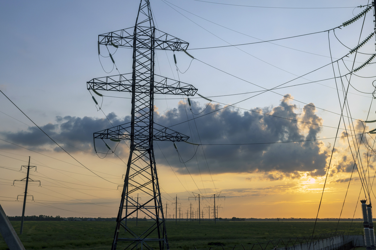 A beautiful photo of an industrial-voltage tower at sunset showcases the benefits of drones in electric utility risk modeling.